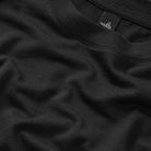 Black virgin wool t-shirt fabric close-up with stitched crew-neck collar and tag