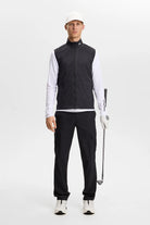 Black packable vest with stand collar and full front zipper, worn by model.