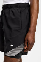 Black athletic shorts with elastic waistband and diagonal striped side panel