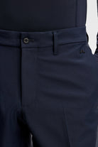 Navy trouser detail with waistband button, belt loops, and front crease