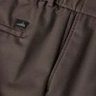 Dark brown trousers with logo label patch and neat stitched waistband detail