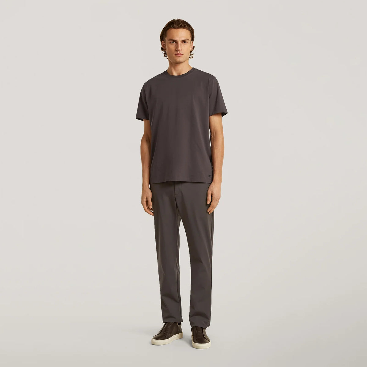 Dark brown tech stretch travel trousers on model, straight leg with cuffed hem