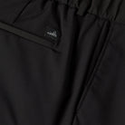 Black tech travel shorts fabric close-up with stitched waistband and small logo label