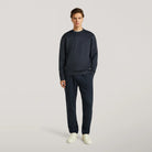Deep navy crewneck sweater with long sleeves and ribbed hem, worn with pants