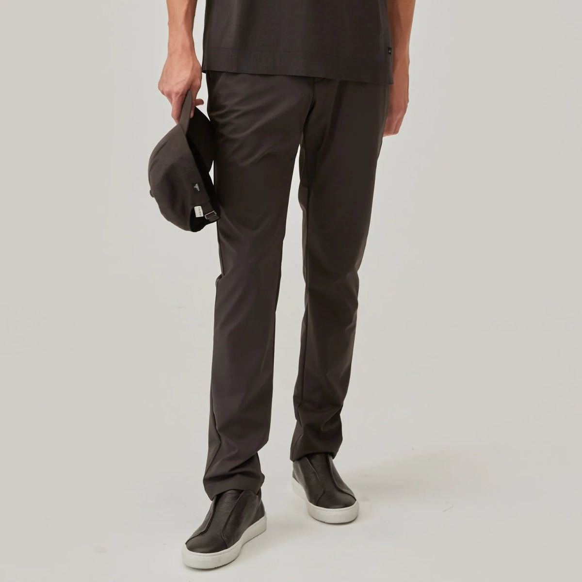 Model wearing dark brown tech trousers with side pocket and straight-leg fit