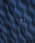 Blue jacquard shirt placket with dark-striped pattern and round logo button