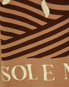 Caramel T-shirt close-up with dark stripes and partial 'SOL E M' lettering.