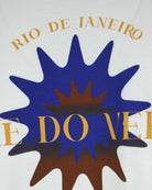 White T-shirt close-up of blue sunburst graphic and golden lettering