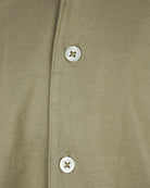 Khaki button placket detail with white buttons on short-sleeve Cuban shirt