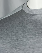 Light grey T-shirt crewneck rib and neckline seam close-up on fabric.