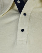 Cream terry polo close-up with textured fabric and button placket