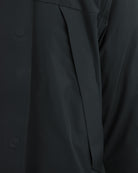Black parka side close-up with angled panel and stitched fabric edge