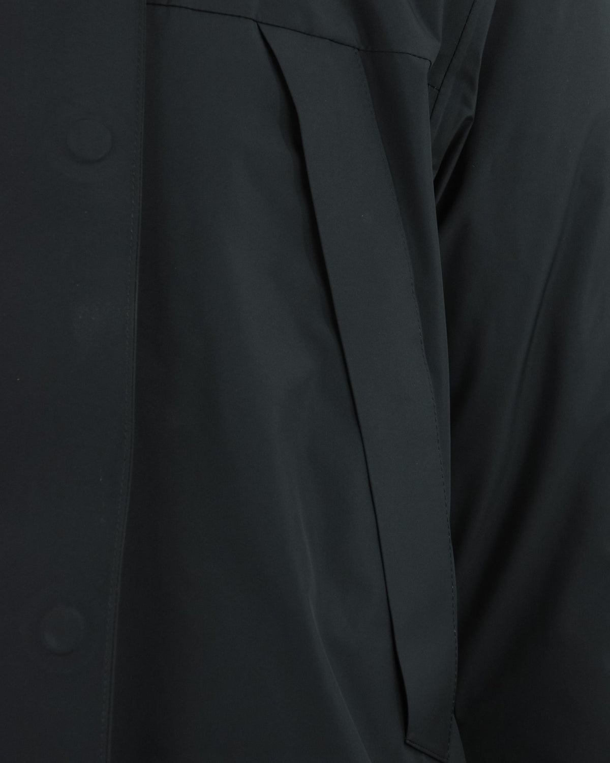 Black parka side close-up with angled panel and stitched fabric edge