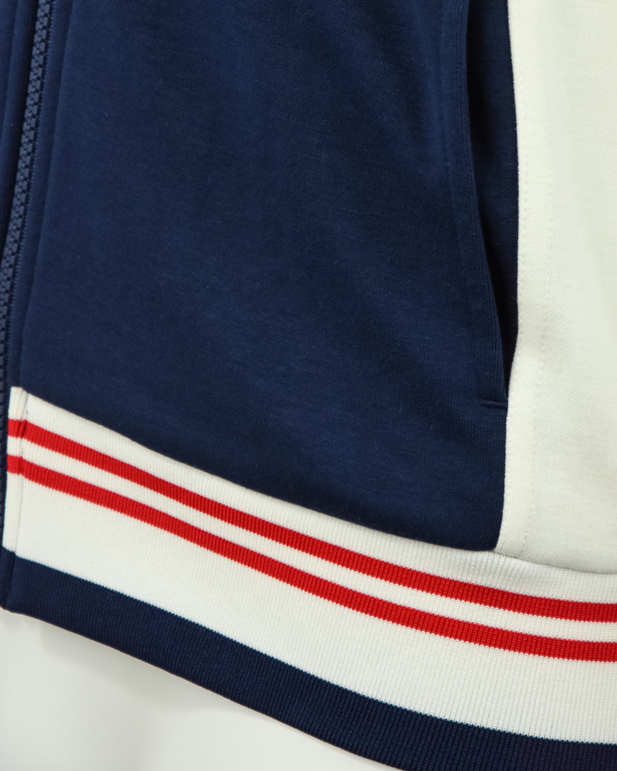 Ribbed striped hem on navy and cream track jacket with red and white bands