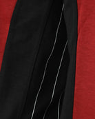 Close-up of black sleeve panel with curved white stripe accents on red fabric.