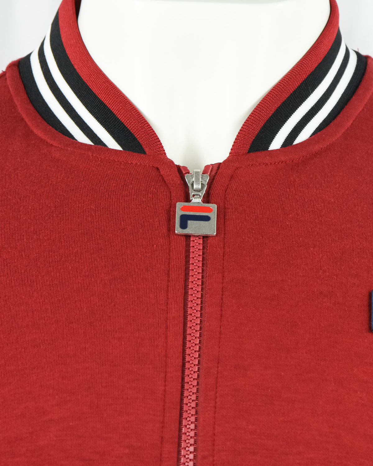 Red baseball track jacket neckline with striped collar and silver zipper pull.