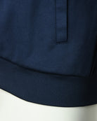 Navy track top close-up of ribbed hem and front panel zip tab