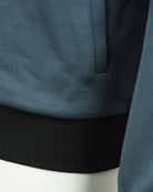 Teal track jacket with ribbed black hem band and sleeve cuff