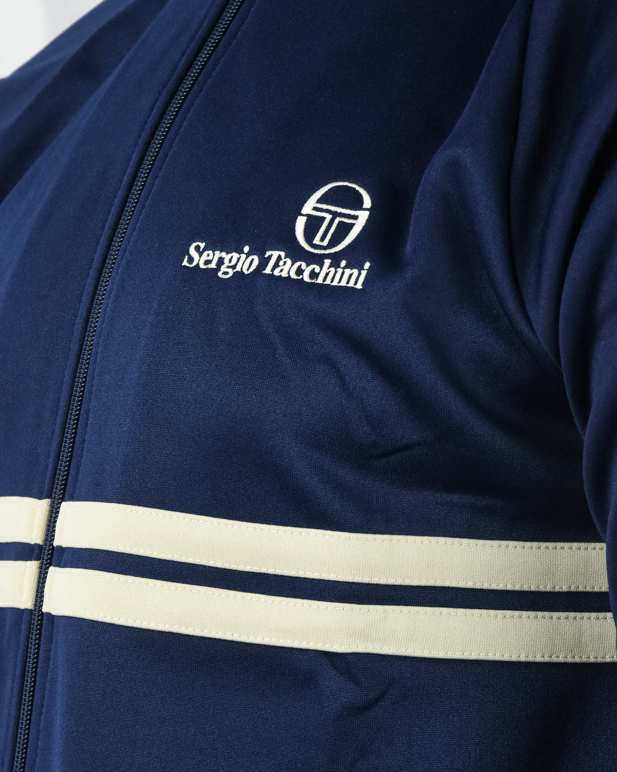 Navy track top jacket with front zipper, cream stripe band, and Sergio Tacchini logo