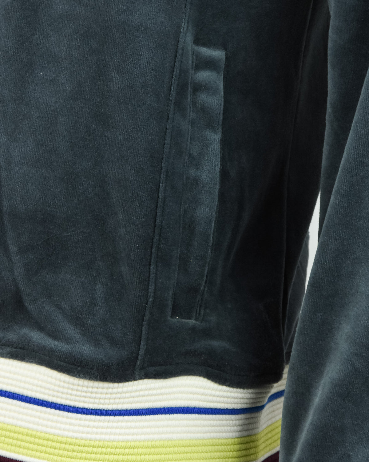 Dark teal velour jacket sleeve with ribbed striped cuff in blue, white, and lime