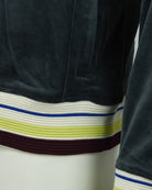 Close-up of dark teal velour hem with multicolor ribbed stripe band