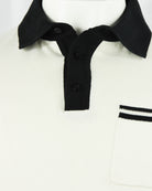 Cream knit polo showing black collar and placket with visible button details.