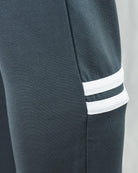 Track pants cuff close-up with dark teal knit and two white stripes