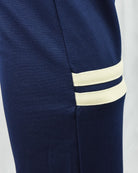 Navy track pants with two-tone cream-and-ivory striped ankle cuffs