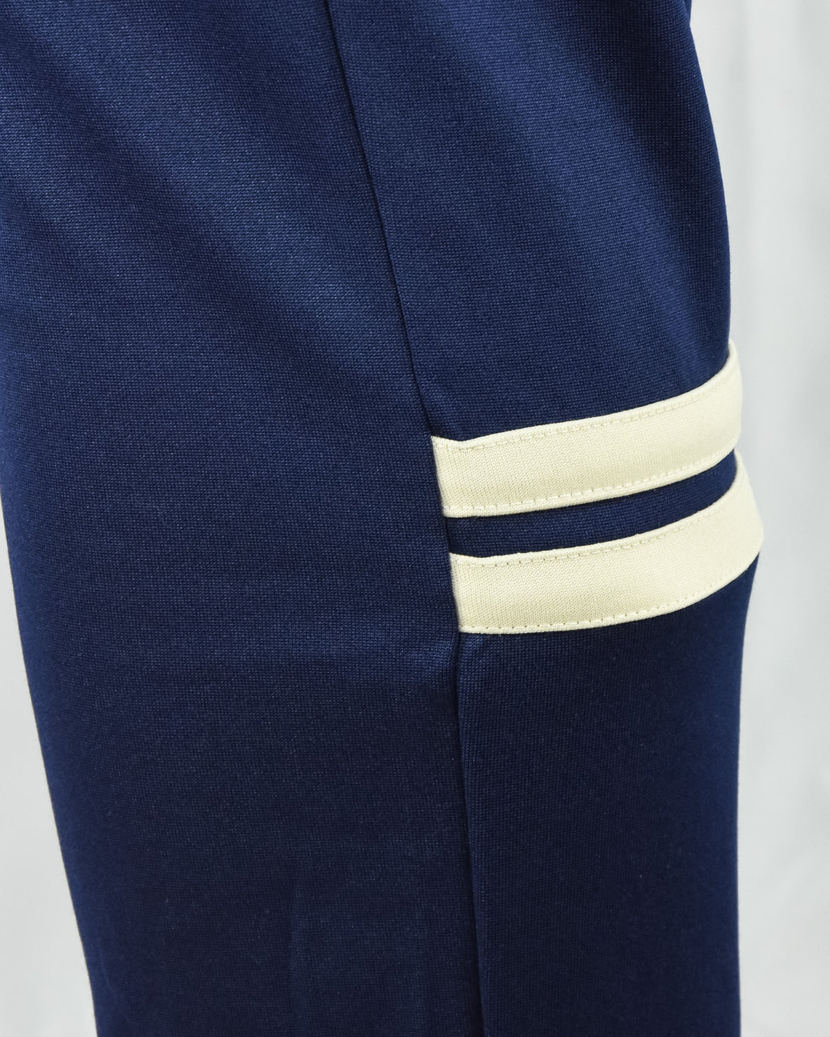 Navy track pants with two-tone cream-and-ivory striped ankle cuffs