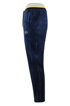 Velour track pants in maritime blue, side view with yellow trim and small logo