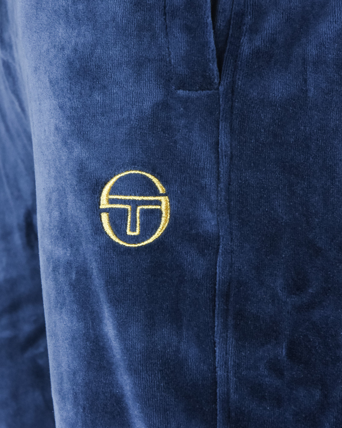 Velour track pants logo patch on blue fabric