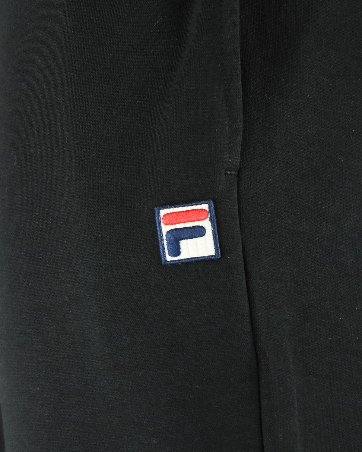 Black pants with embroidered Fila logo patch on the side seam
