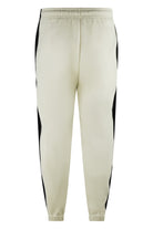 Cream track pants with black side panels and elastic cuffs, front drawstring