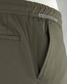 Olive pants close-up: 'REGULAR' label, slanted pocket opening, double-stitched seams