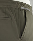 Olive pants close-up: 'REGULAR' label and side pocket seam with welt detailing