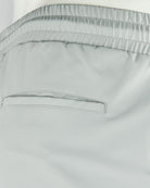Stone grey tech pants waistband close-up with elastic channel and stitched seams