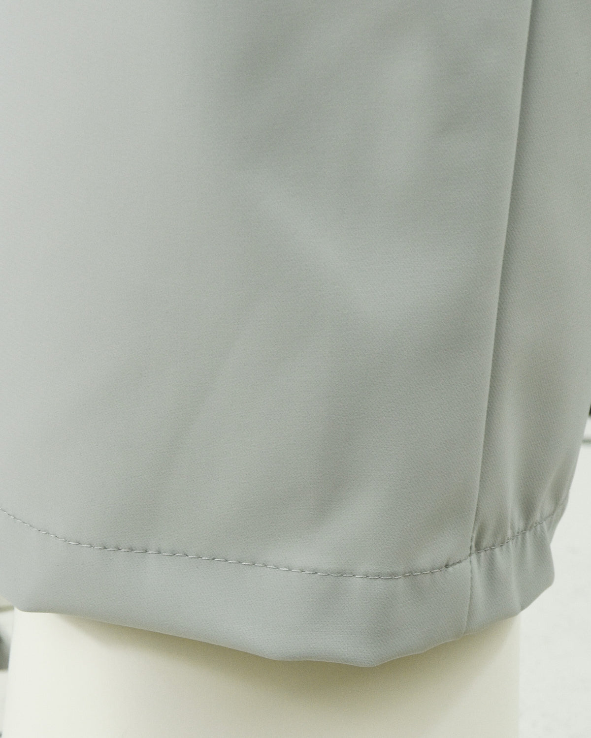 Stone grey tech pants hem and stitched pocket underlayer close-up