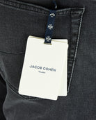 Jacob Cohen Milano hang tag attached to dark grey denim jeans pocket.