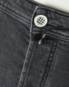Dark grey jeans zipper fly with round button and belt-loop detail.