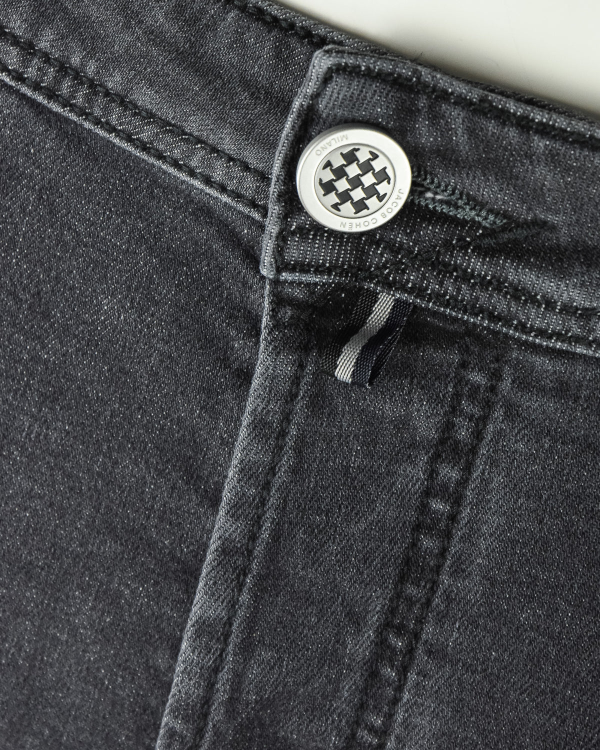 Dark grey jeans zipper fly with round button and belt-loop detail.