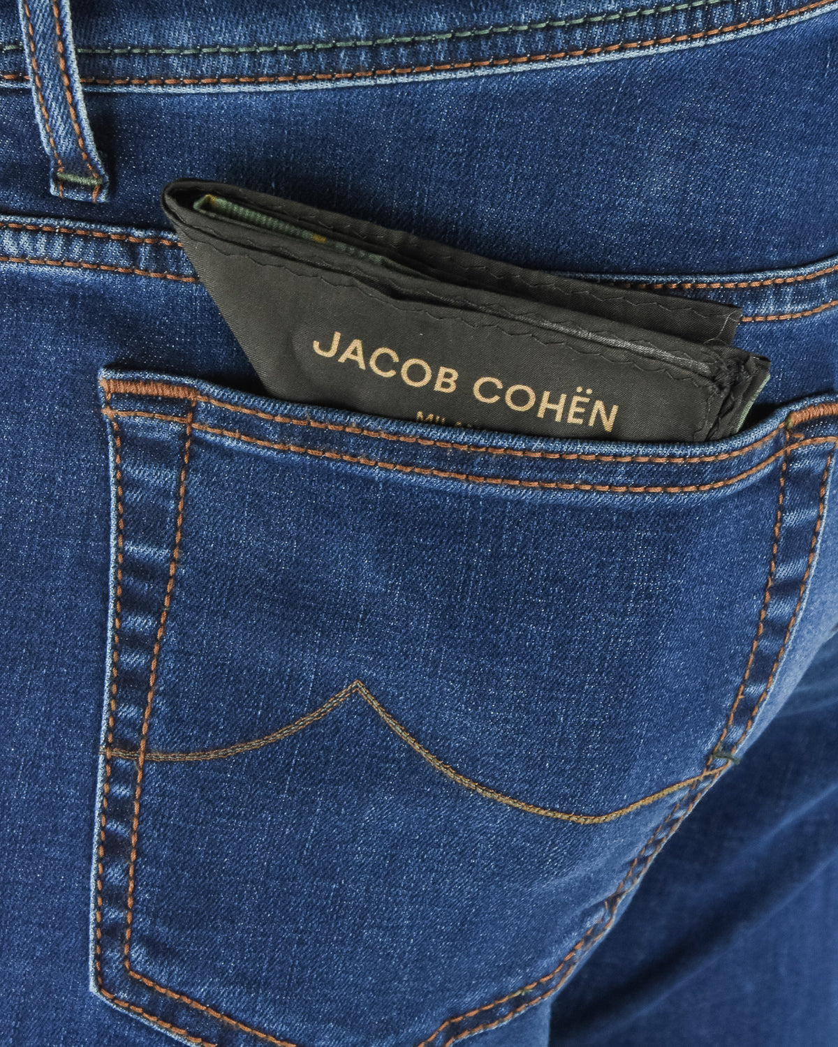 Blue denim front pocket with dark brand badge and contrast orange stitching