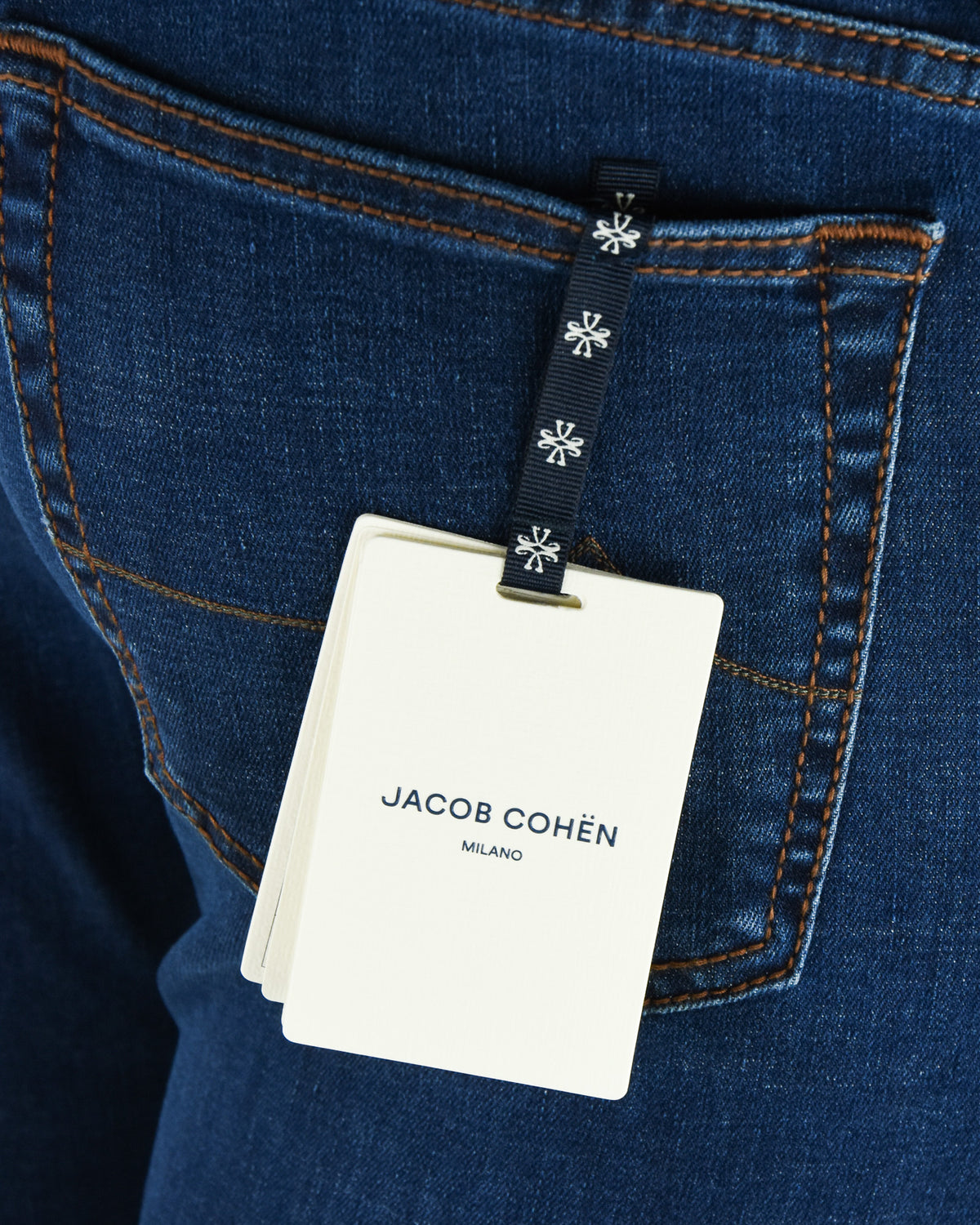 Blue denim jeans with black patterned loop tag and white brand card