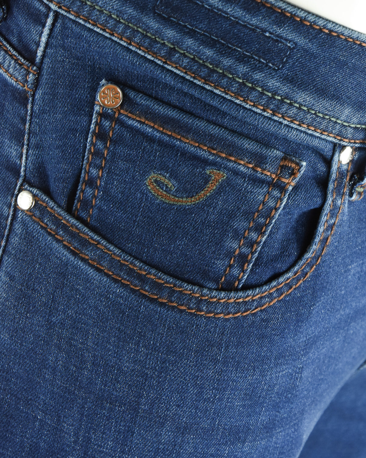 Blue denim jeans coin pocket with orange topstitching and metal button