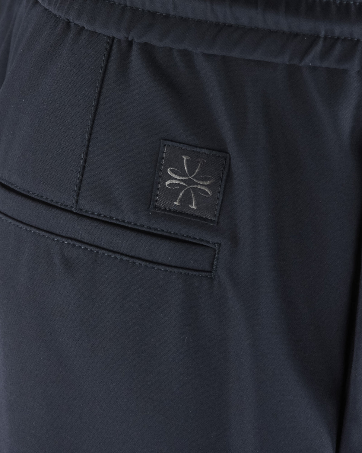 Navy tech pants with stitched logo patch on pocket flap