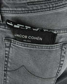 Denim jeans waistband close-up with Jacob Cohen logo patch and stitched inner trim