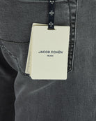 Denim jeans back pocket with hanging brand tag on grey stretch fabric