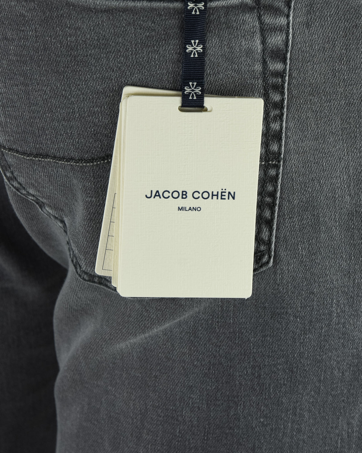 Denim jeans back pocket with hanging brand tag on grey stretch fabric