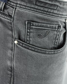 Back pocket close-up on light grey denim jeans with small logo emblem