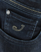 Front pocket with stitched smile graphic and small metal rivet on dark denim.