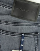 Jacob Cohen Milano waistband label with navy hang tag on grey denim jeans